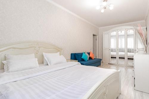 a bedroom with a large white bed and a blue couch at Apartments 7 Я-14 in Astana