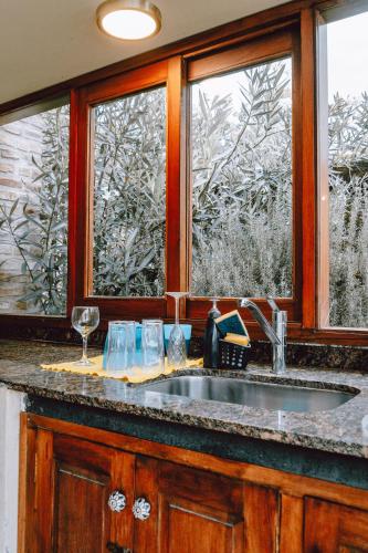 a kitchen counter with a sink and two windows at El Colonial Departamentos in Cafayate