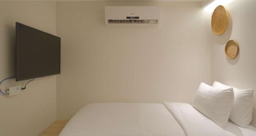 a bedroom with a white bed with a tv on the wall at SimpleStay Chatuchak, SureStay Collection by Best Western in Bangkok