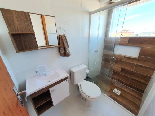 a bathroom with a toilet and a glass shower at Linda casa 3 Praia Ponta do Papagaio 190mt mar in Palhoça
