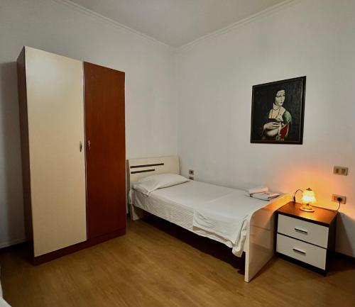 a small bedroom with a bed and a desk and a picture at Grand House Rooms in Tirana
