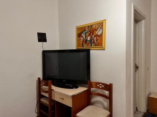 a room with a desk with a television and a painting at Grand House Rooms in Tirana