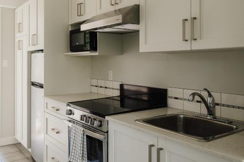 a white kitchen with a sink and a stove at Gibsons Landing Inn in Gibsons