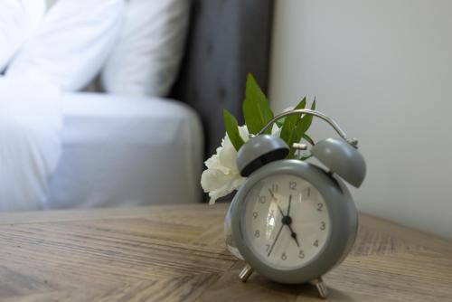 a clock sitting on a table with a flower at Aqua on the Edge in Airlie Beach