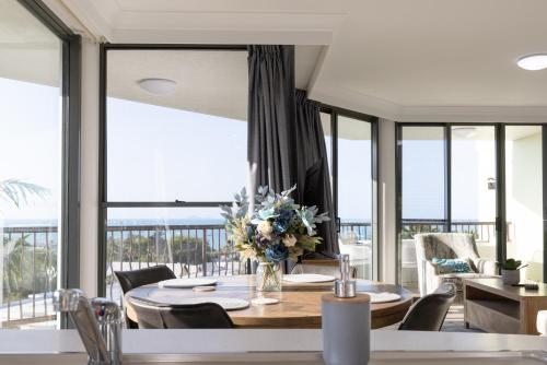 a dining room with a table and chairs and windows at Aqua on the Edge in Airlie Beach