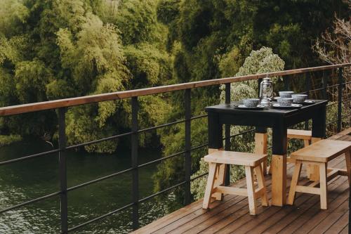 a table and chairs on a deck with a view of a river at KABINE in El Peñol