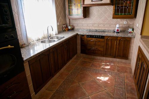 a kitchen with wooden cabinets and a sink and a window at Casa Rural LA ENCINA in Hornachuelos