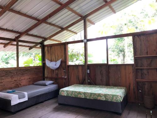 two beds in a wooden room with windows at Cabaña Espavé - Arusí, Chocó in Nuquí