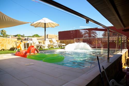 a pool with a water slide and an umbrella at Casa Rural LA ENCINA in Hornachuelos