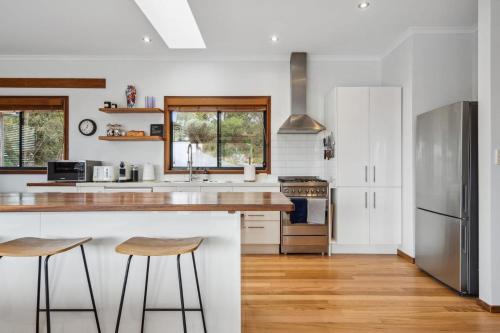 a kitchen with white cabinets and a counter with stools at Charming 4 Bed Home in Mount Victoria in Mount Victoria