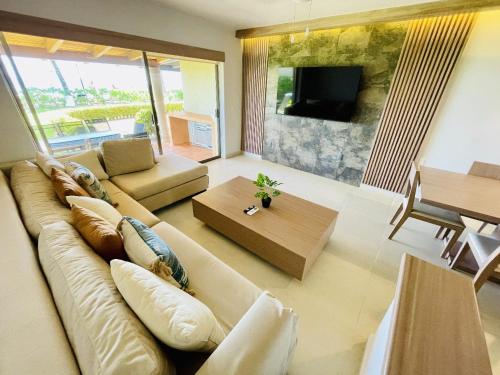 un salon avec un canapé, une télévision et une table dans l'établissement Villa 8 frente al mar, à Zihuatanejo