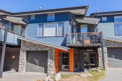 a blue building with an orange door and a balcony at Powder 2B - Thredbo in Thredbo