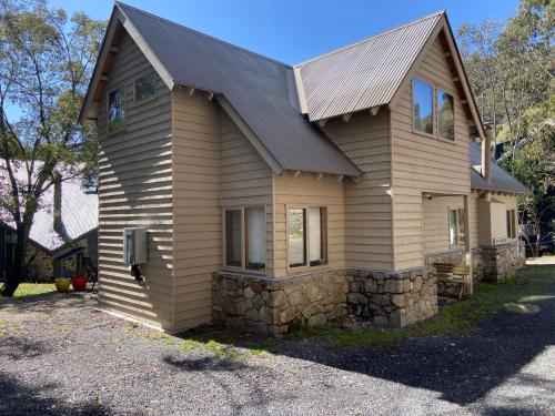 a small house with a stone wall at Bollygums - Thredbo in Thredbo