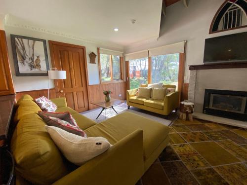 a living room with a yellow couch and a fireplace at Bollygums - Thredbo in Thredbo