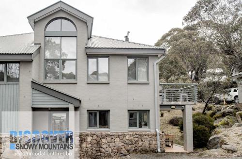 a house with a stone facade with a balcony at Wintergreen 3 - Thredbo in Thredbo