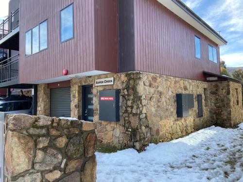 a stone wall in front of a building at Aspen Creek 5 - Thredbo in Thredbo
