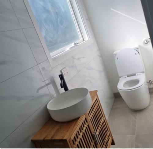 Un baño con inodoro, lavabo y ventana. en cosy studio in east Gippsland B, en Paynesville