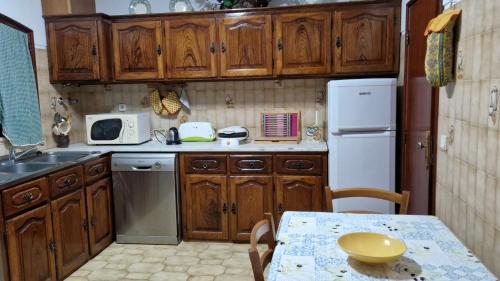 a small kitchen with wooden cabinets and a table with a tableablish at Casa Macedo in Alfândega da Fé