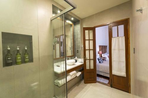 a bathroom with a glass shower with a sink and a toilet at On Hotel Boutique in Sucre