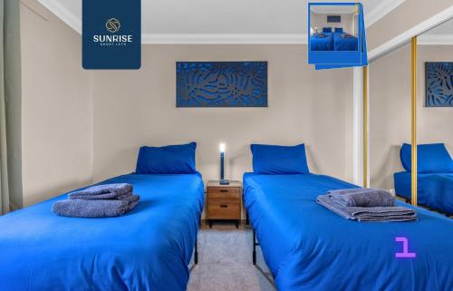 two beds in a room with blue sheets at Muirton House 2 - INVOICE and REDUCED PRICE only via SUNRISE SHORT LETS DUNDEE, SLEEPS 8 has 4 Twin Bedrooms with 4 Car Driveway, 2 Bathrooms, Smart TV, Fully Equipped Kitchen, Large Dining and Living Space, Rear Garden, Free WiFi, Long Stays in Dundee