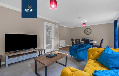 a living room with a tv and a couch and a table at Muirton House 2 - INVOICE and REDUCED PRICE only via SUNRISE SHORT LETS DUNDEE, SLEEPS 8 has 4 Twin Bedrooms with 4 Car Driveway, 2 Bathrooms, Smart TV, Fully Equipped Kitchen, Large Dining and Living Space, Rear Garden, Free WiFi, Long Stays in Dundee