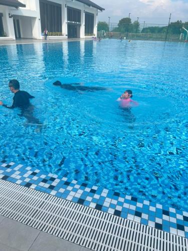two people in a swimming pool with a whale in the water at Amliza homestay in Cyberjaya