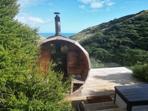 a small wooden cabin with the ocean in the background at Raglan Lovebus in Raglan