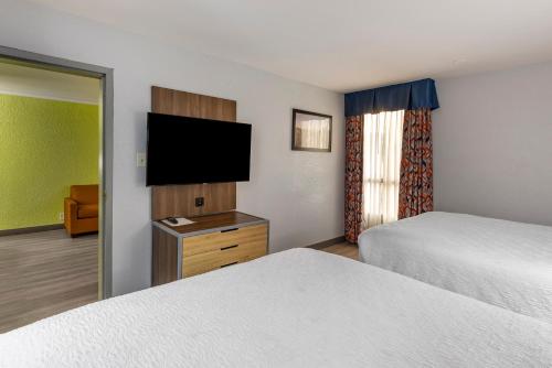 a hotel room with two beds and a flat screen tv at Best Western Plus St. Louis West-Westport in Maryland Heights