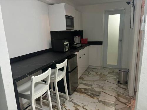 a kitchen with two white chairs and a counter at El refugio de Los Ángeles in San Juan