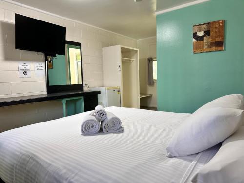 a bedroom with a white bed with towels on it at Kalka Palms Hotel Motel in Rockhampton