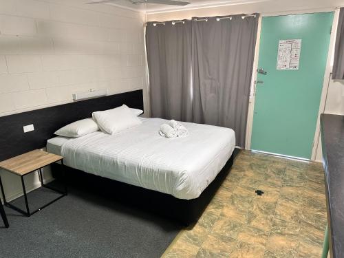 a small bedroom with a bed and a table at Kalka Palms Hotel Motel in Rockhampton