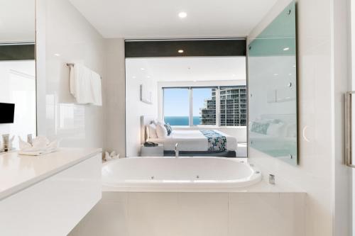a white bathroom with a tub and a window at Q1 Resort & Spa - Official in Gold Coast
