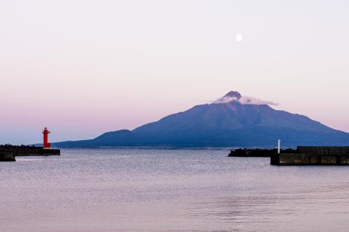 a mountain and a red lighthouse in the water at REBUN Hotel SARYO in Kafuka