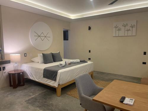 a bedroom with a bed and a table and a chair at Hotel Casa Barbara Holbox in Holbox Island