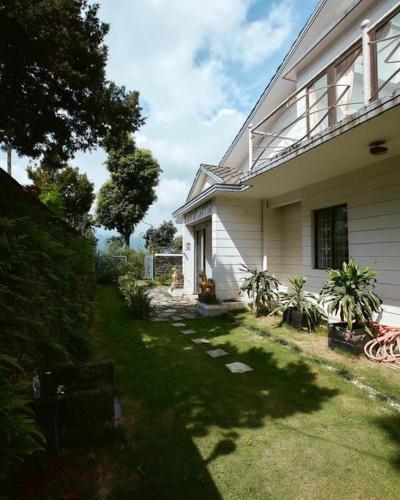 a house with a grass yard next to a building at Ghost Villa Pokhara with mountain view 20mins from main area in Rānīpauwa