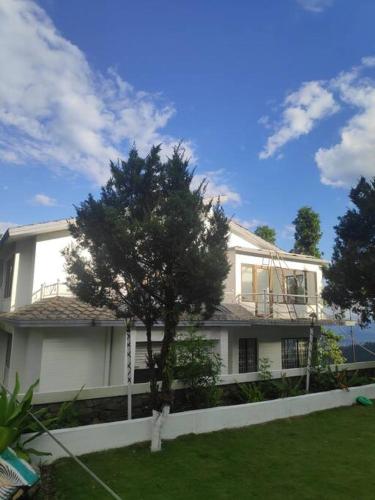 a white house with a tree in front of it at Ghost Villa Pokhara with mountain view 20mins from main area in Rānīpauwa