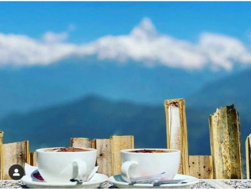 two cups of coffee on a table next to a fence at Ghost Villa Pokhara with mountain view 20mins from main area in Rānīpauwa
