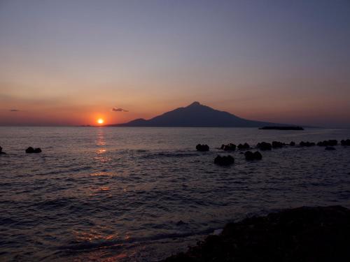 a sunset over the ocean with a mountain in the background at REBUN Hotel SARYO in Kafuka