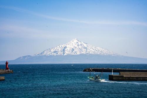 a mountain in the ocean with a boat in the water at REBUN Hotel SARYO in Kafuka