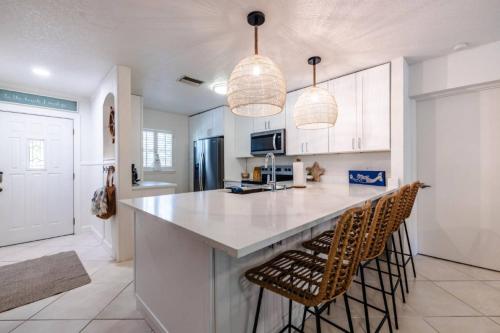 a kitchen with a large island with two bar stools at Catch the Breeze on Crystal Beach in Palm Harbor