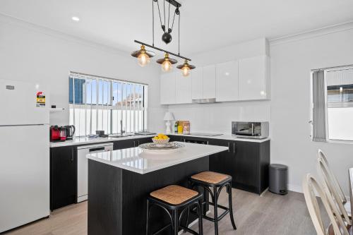 a kitchen with black and white cabinets and a table at C-Views - Aldinga Beach - C21 SouthCoast Holidays in Aldinga Beach