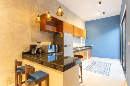 a kitchen with a counter and some chairs in it at Casa Mercedes - Stylish & Historic in heart of Mérida in Mérida