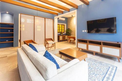a living room with a white couch and a tv at Casa Mercedes - Stylish & Historic in heart of Mérida in Mérida
