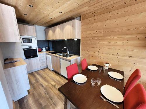 une cuisine avec une table en bois et des chaises rouges dans l'établissement Résidence Cry De Lys - Appartement entièrement rénové, au pied des pistes MAE-8491, aux Gets