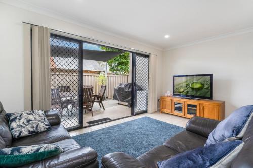 a living room with a couch and a flat screen tv at LaBellaVita 26 Landsborough St SWR in South West Rocks