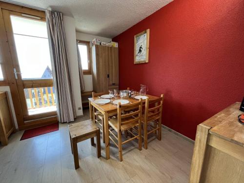 une salle à manger avec une table et un mur rouge dans l'établissement Studio rénové de 26 m² pour 4 pers avec balcon, accès pistes, animaux admis - Vallandry - FR-1-757-116, à Landry