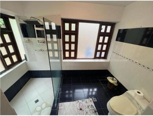 a bathroom with a toilet and a glass shower at DAPA CASA CAMPESTRE CON PISCINA y JACUZZI in Dapa