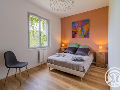 a bedroom with a bed and a chair in it at Maison rénovée avec jardin proche d'Angers - FR-1-622-92 in Rochefort-sur-Loire