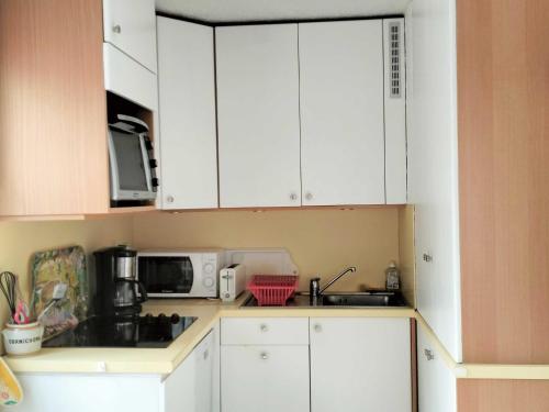 une cuisine avec des armoires blanches et un micro-ondes dans l'établissement Beau T2 cabine avec parking privé à Villard-de-Lans - FR-1-761-44, à Villard-de-Lans