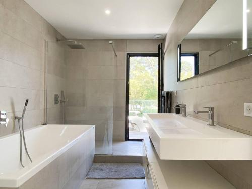 - une grande salle de bains blanche avec deux lavabos et une baignoire dans l'établissement Villa d'Exception avec Piscine et Jardin Proche Plages et Lac à Hossegor - FR-1-791-5, à Soorts-Hossegor